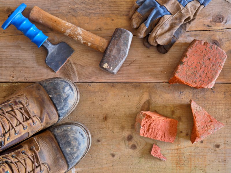 Outils, gants et chaussures de chantier posés sur un plan de travail en bois
